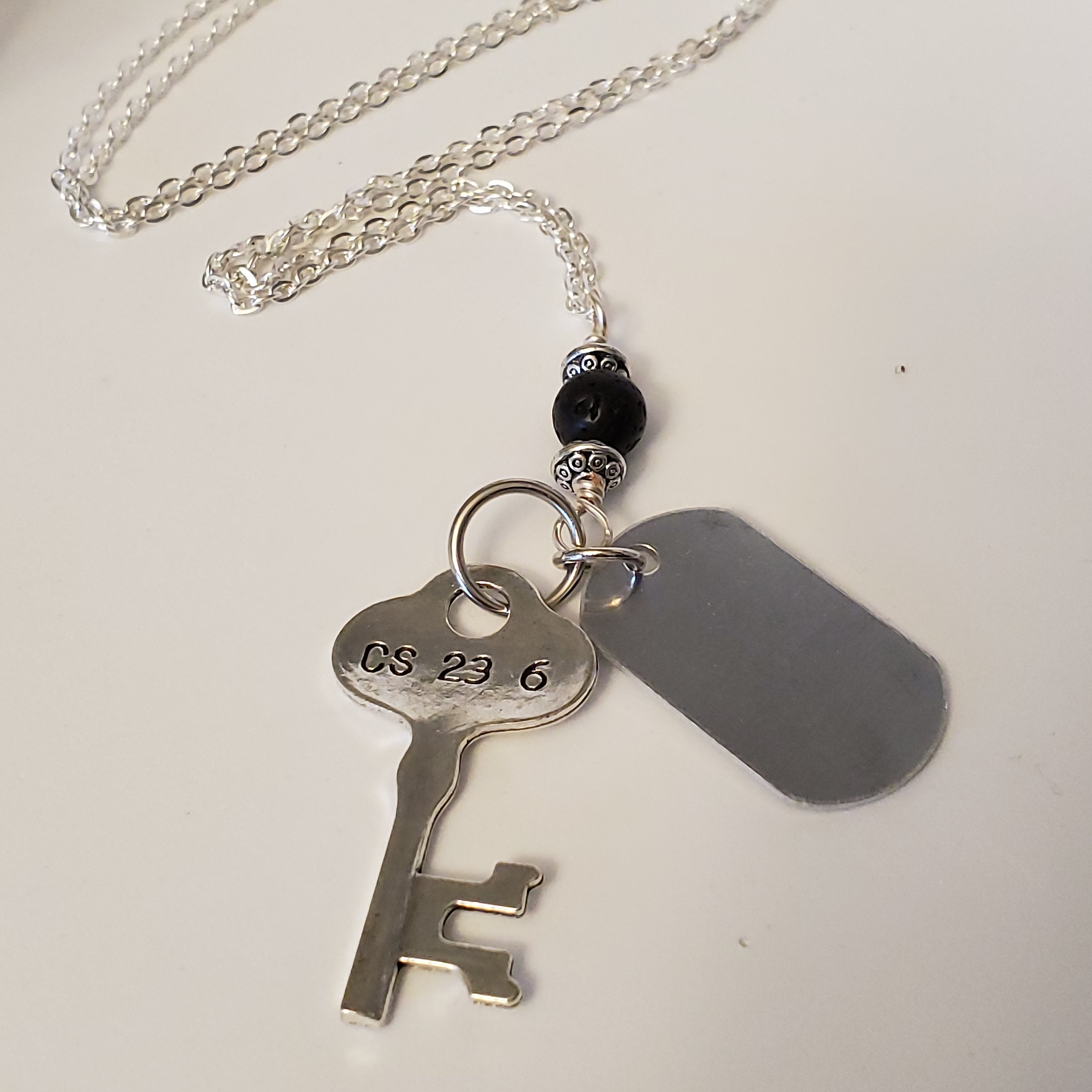 Key-shaped charm, dog tag and black lava bead