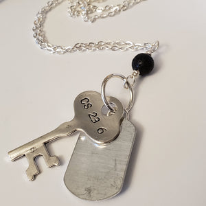 Long chain necklace with key-shaped charm, dog tag and black lava bead