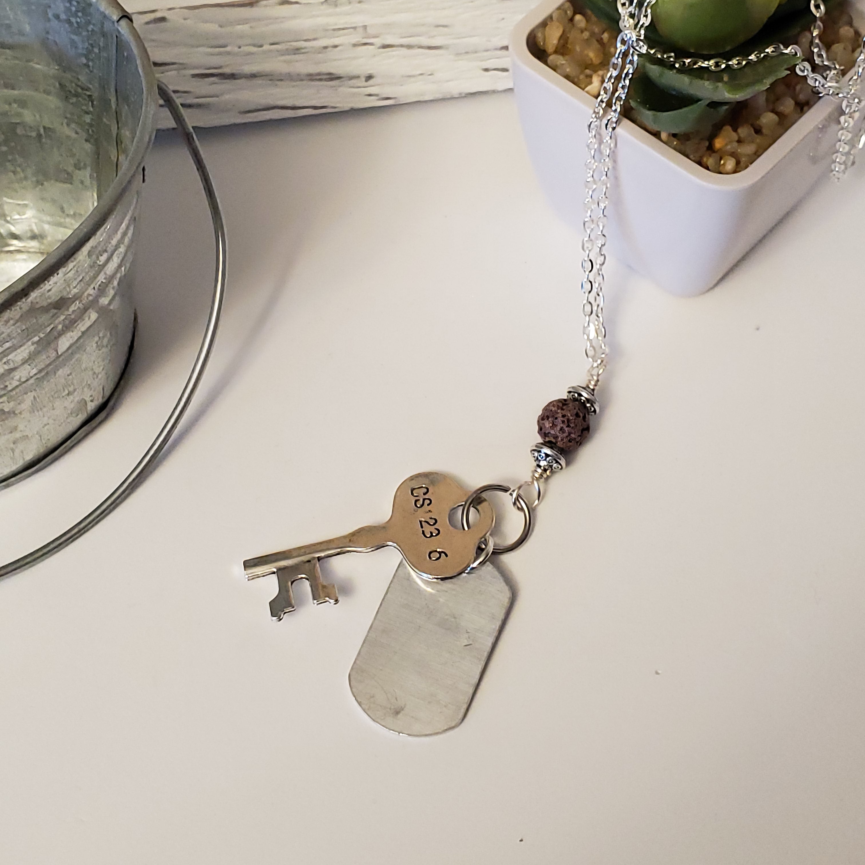 key-shaped charm with dog tag and brown lava bead
